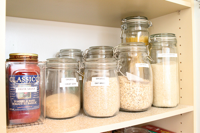 Clear glass jars with sugar and flour and pasta sauce on the shelf.