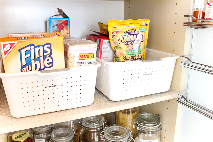 Crackers and cookies in white bins on the shelf.