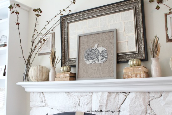 There is a fall mantel with pumpkins and leaves plus books on it.