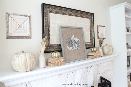 Antique books on the mantel with gold pumpkins on top of them.