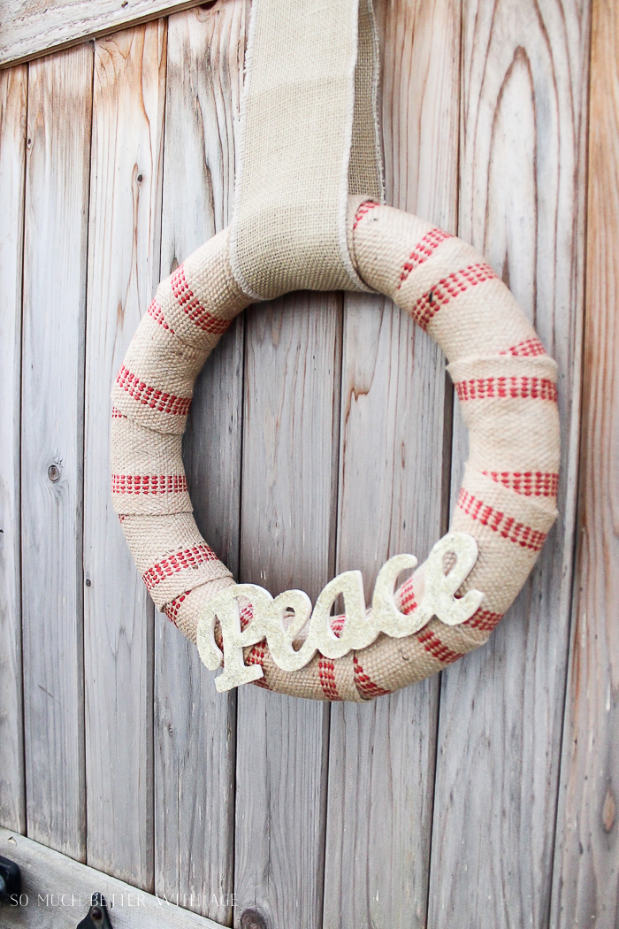 Jute wreath hanging on fence outside.