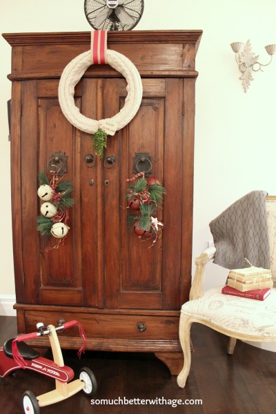 The armoire with the wreath on it and a vintage tricycle beside it.