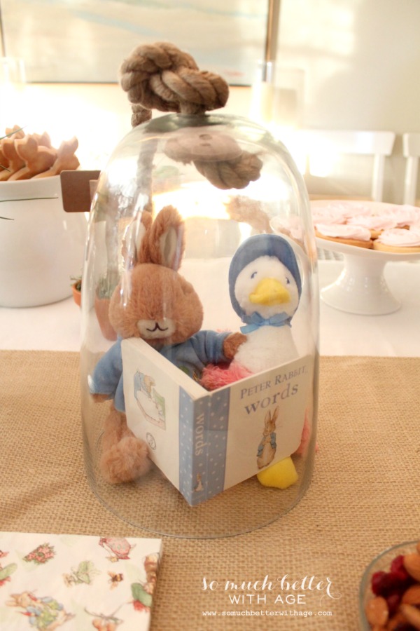 Peter rabbit and jemima puddle duck in a glass cloche reading a book.