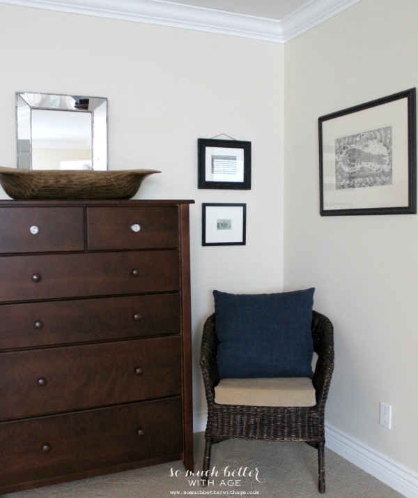 A wooden dresser with a mirror on it and a small chair beside it in the bedroom.