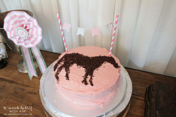 A pink pony cake the table.