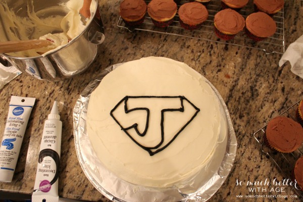 Using remade icing with fine tips drawing the superhero look on the top of the cake.