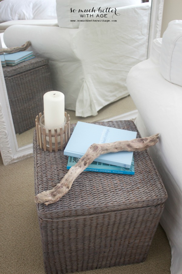 A candle, driftwood, and books on top of the basket.