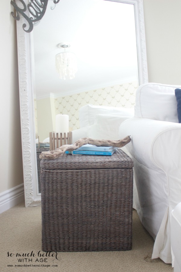 The grey wicker basket in front of a large white mirror.