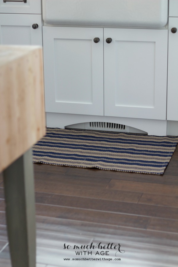 A striped rug in front of the kitchen sink.