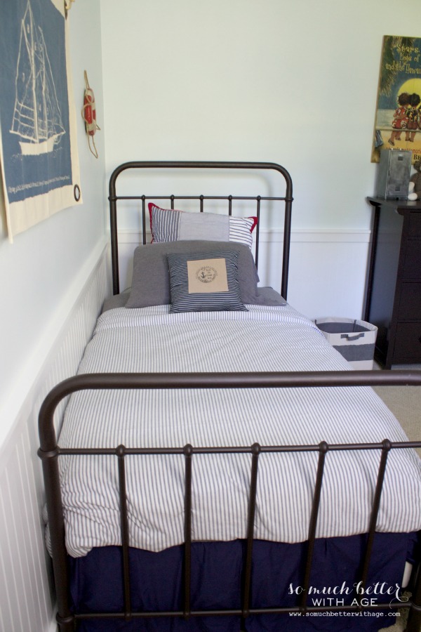 Wrought iron bed with nautical pillows on it.