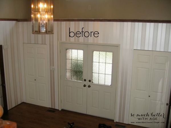 A before picture of the foyer with an outdated light fixture, striped wallpaper.