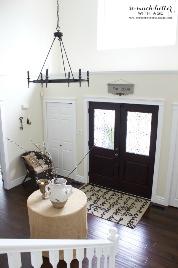 Foyer with rug and table and chandelier.