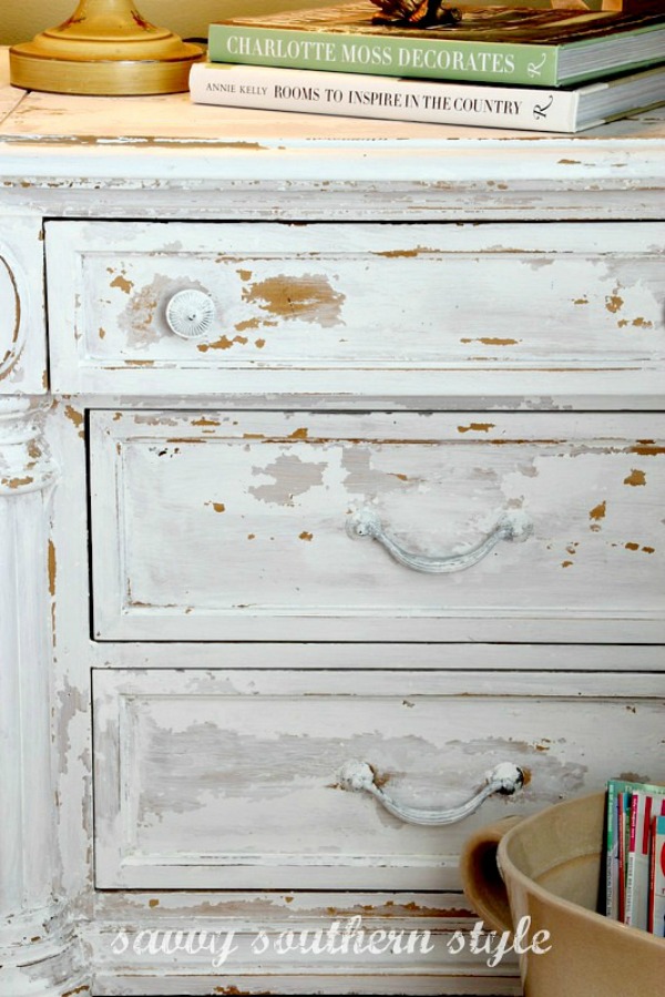 Up close picture of a white chipped paint dresser.