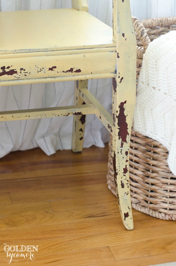 A soft yellow distressed chair beside a wicker basket.