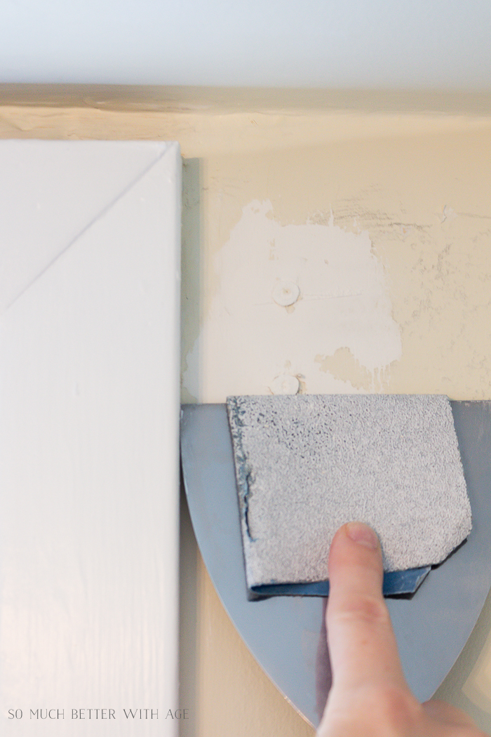 Using sandpaper on a putty knife on the wall anchor.