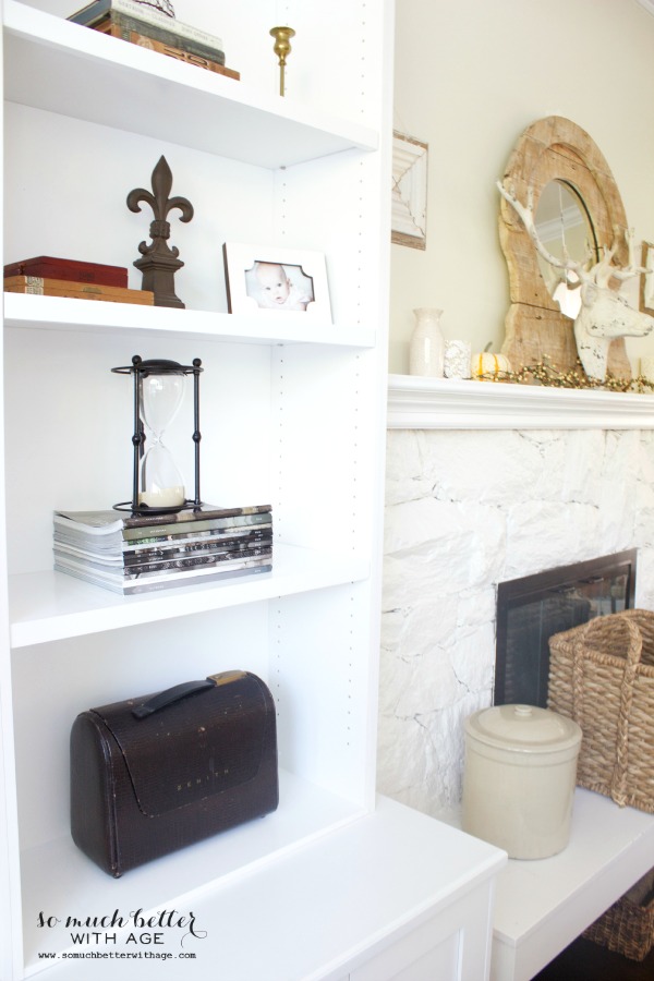 Open white shelves beside the fireplace with magazines on them.