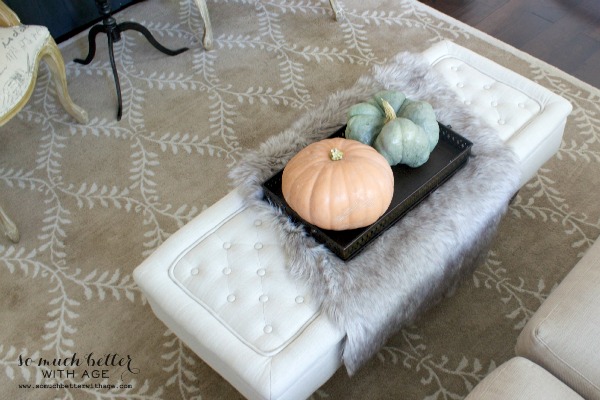 A faux fur blanket on top of the white ottoman.