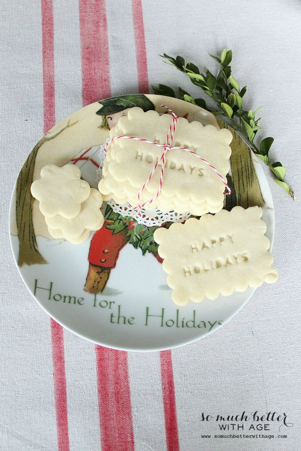 Shortbread cookies on a holiday plate with a sprig of greenery beside it.