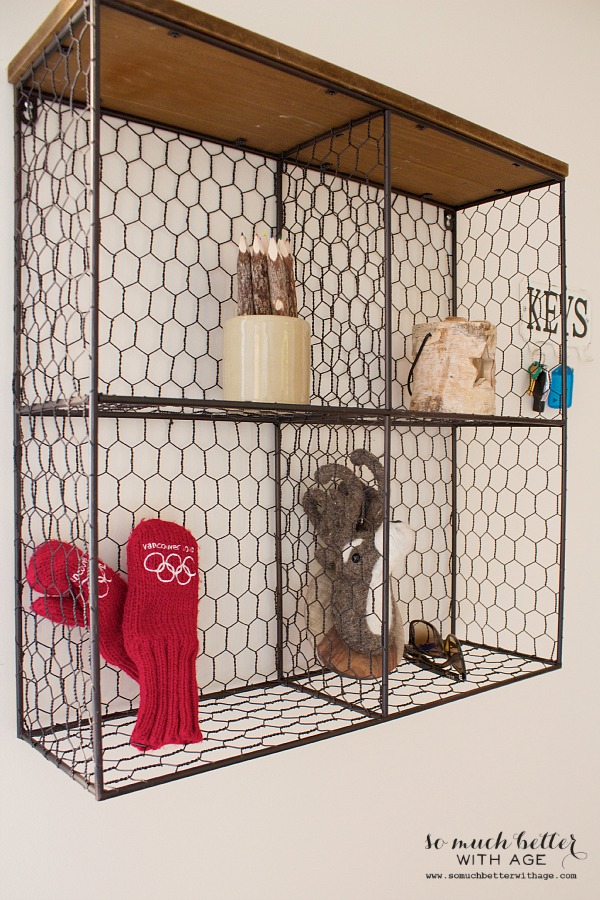 There are mittens, sunglasses and decor items on the wire shelf.