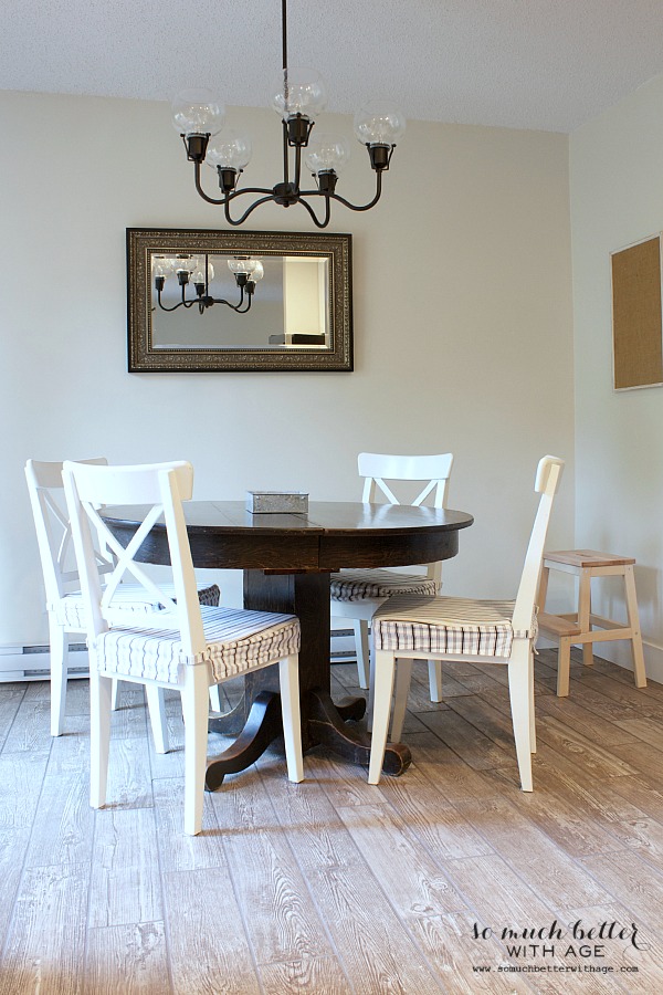 There is a round dining room table with a mirror on the wall.