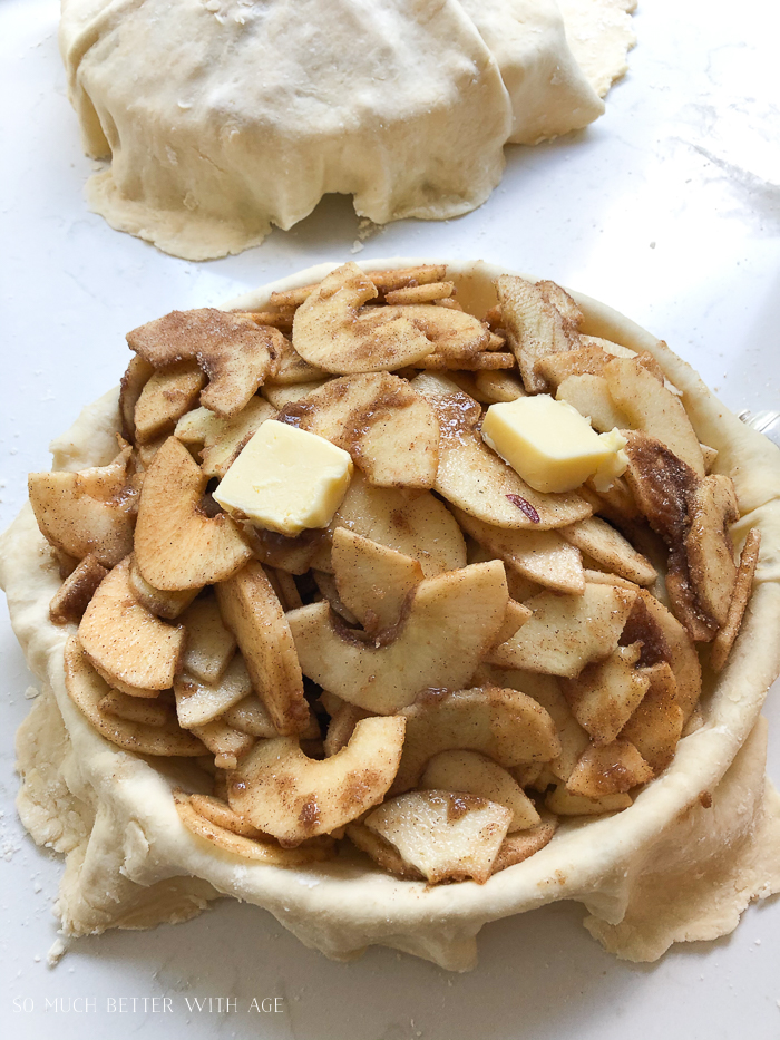 The sliced apples, with cinnamon and brown sugar in the pie crust dotted with butter.