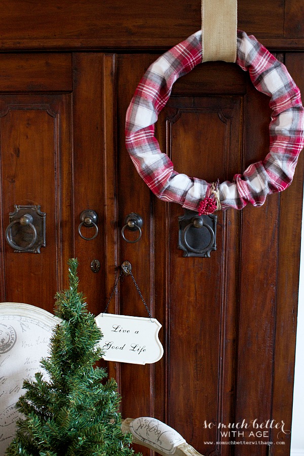 The red plaid wreath on the door with a burlap ribbon.