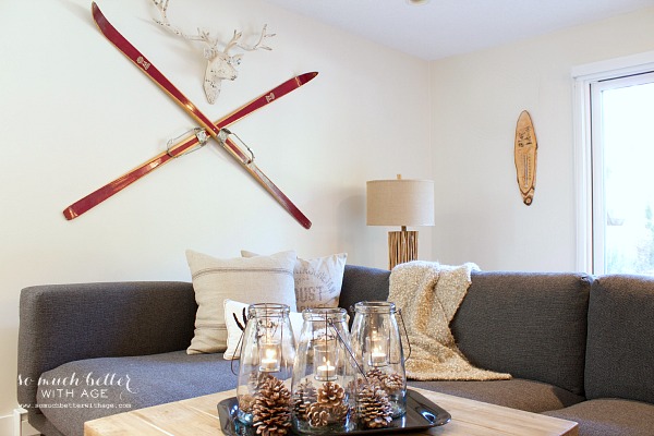 On the living room wall there are skis with a deer head above them.