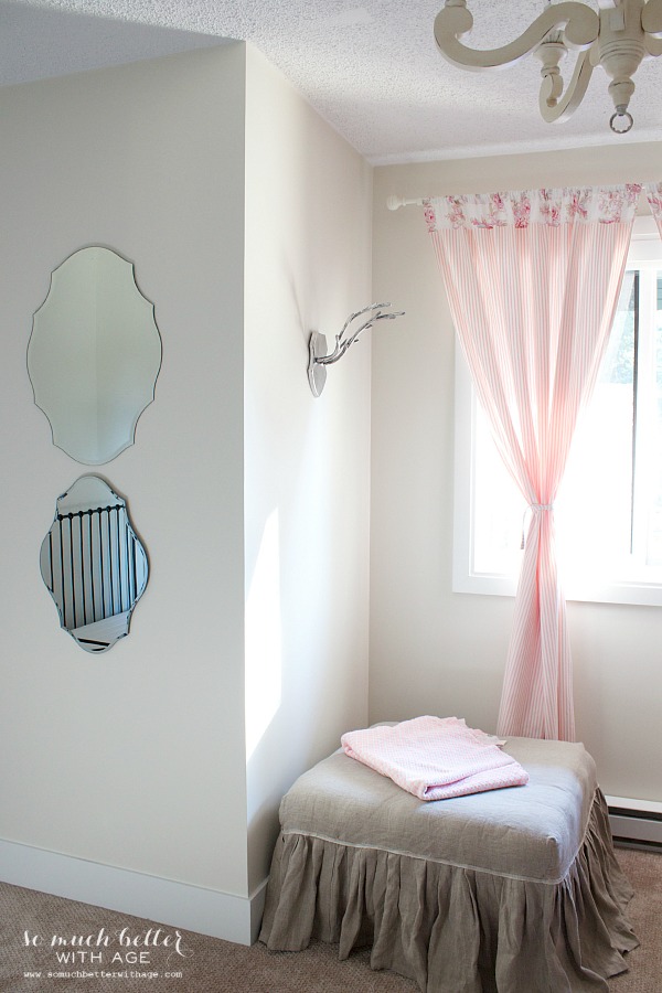 Antlers on the wall beside pink curtains.