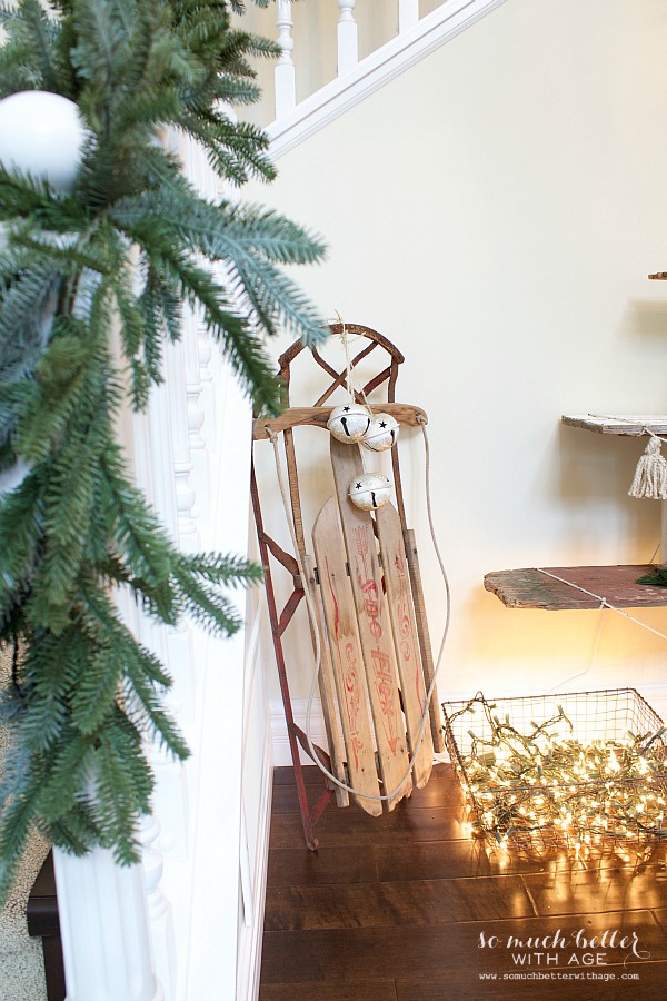 A wooden sleigh is beside the Christmas tree.
