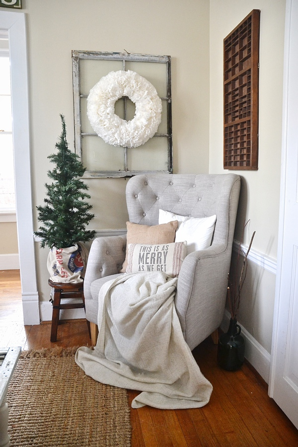 A grey armchair with a white blanket and pillows on the chair.
