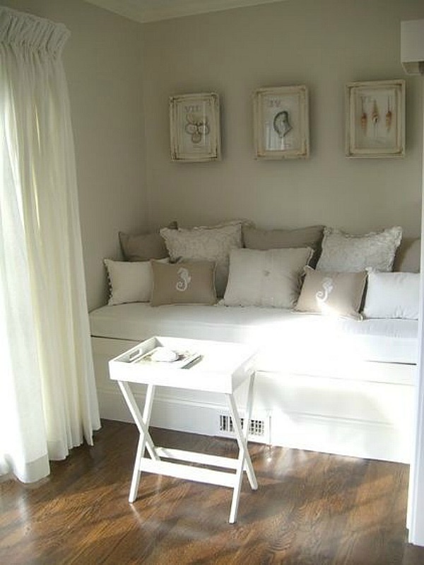 A daybed in a room with a lot of white and beige pillows on it.