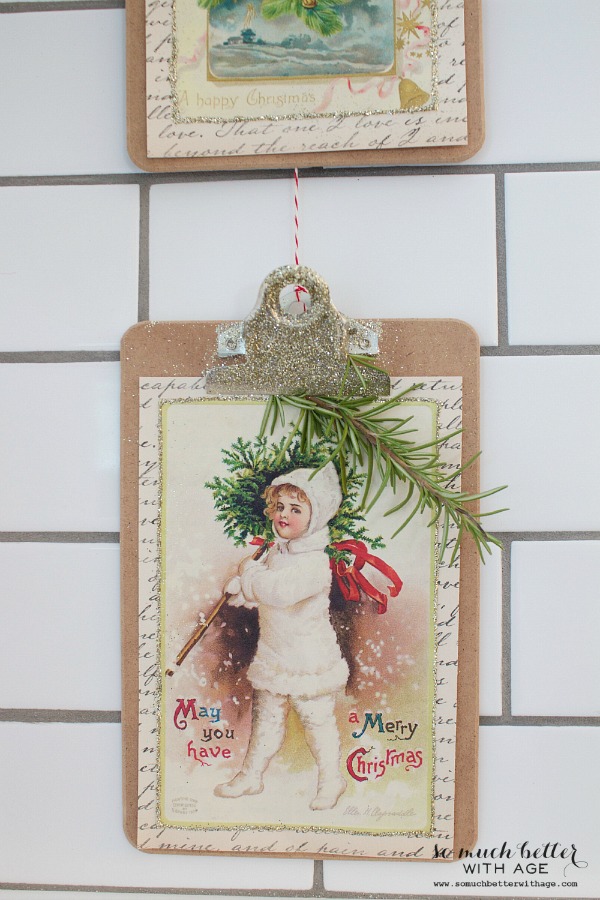 Glitter clipboards hanging up with a sprig of evergreen on them.