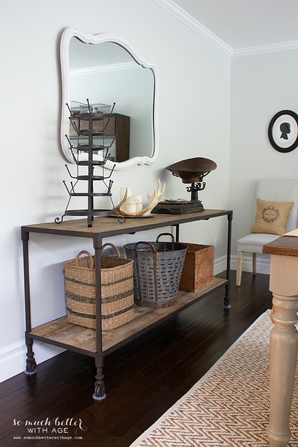 Industrial cabinet with wrought iron legs and a large mirror above it on the wall.