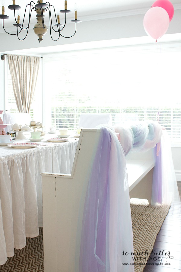 A white bench at the table with tulle around the back of it.