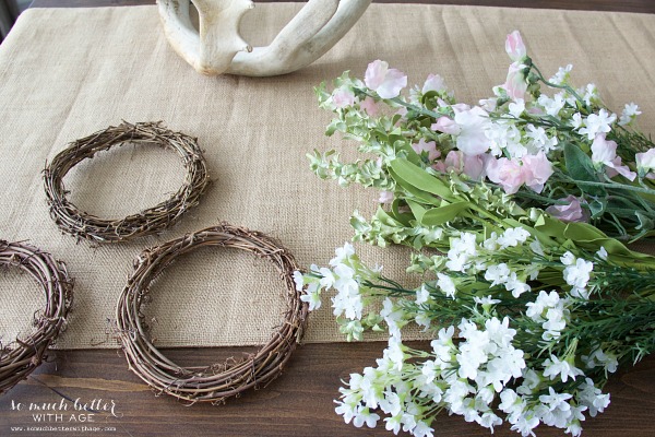 A bundle of flowers on the ground with a grapevine wreath.