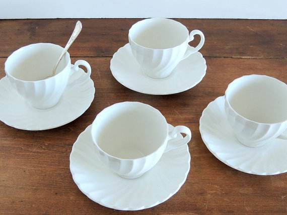 4 white tea cups and a spoon in one.