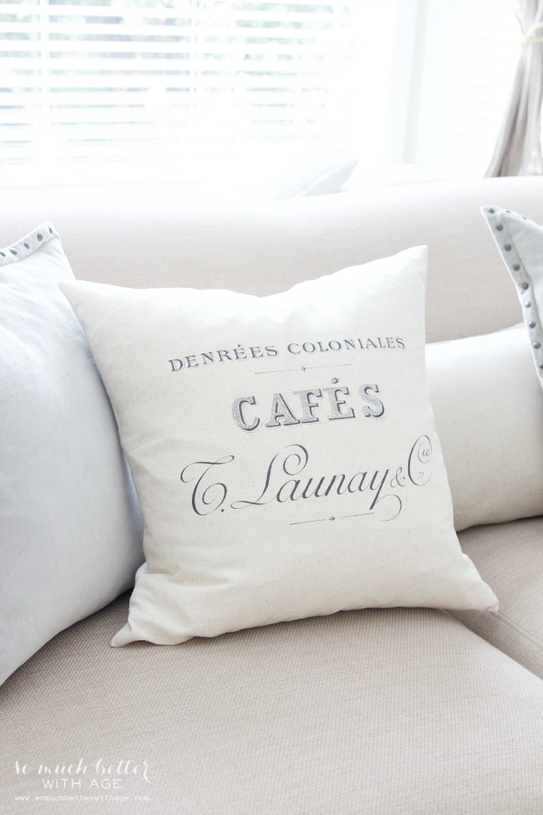 White pillow with grey font on couch.