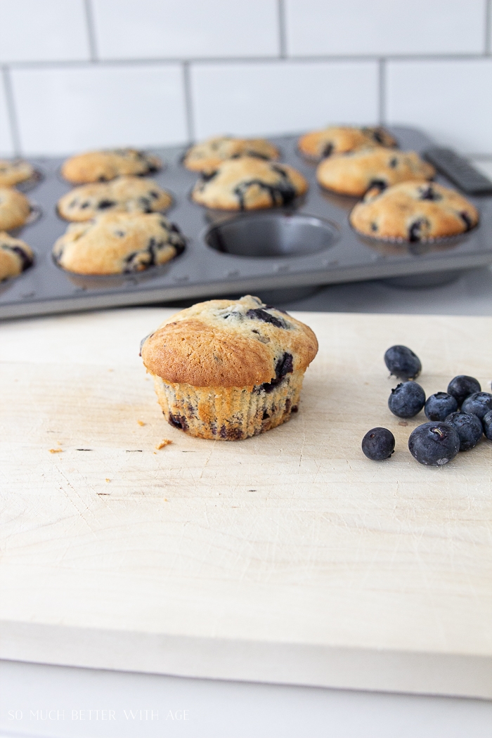 Blueberry muffins baked with one on the counter.