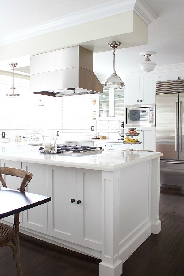 An all white and steel kitchen with a dark floor.