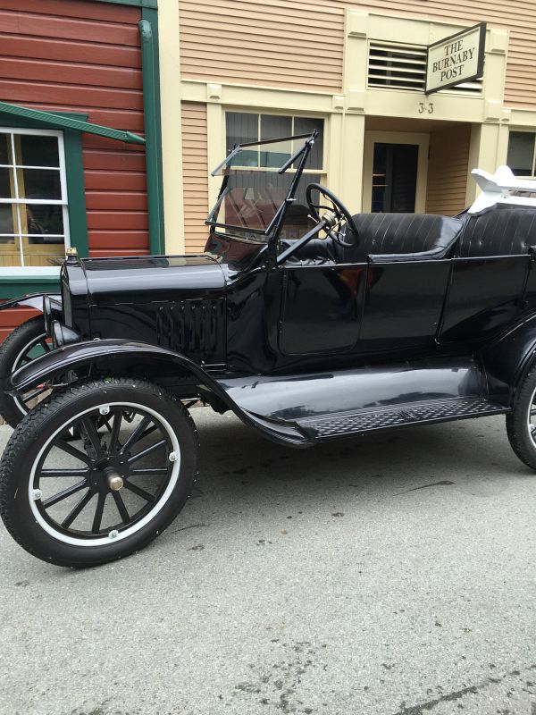A black antique car parked in front of the post office.