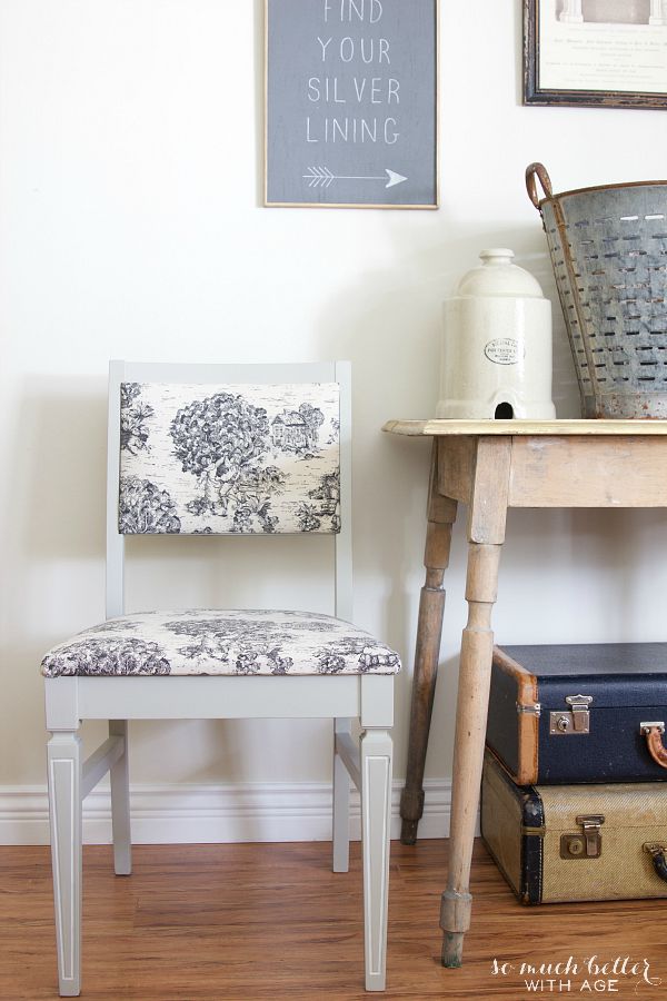 Toile fabric chair beside a wooden side table.
