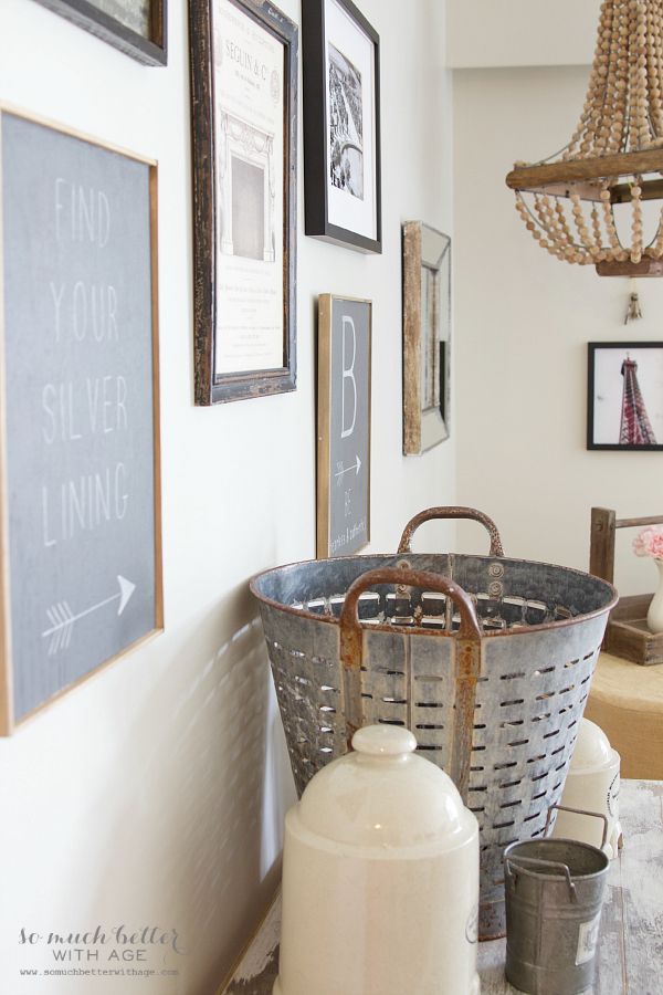 Side table with steel bucket and wooden chandelier in background.