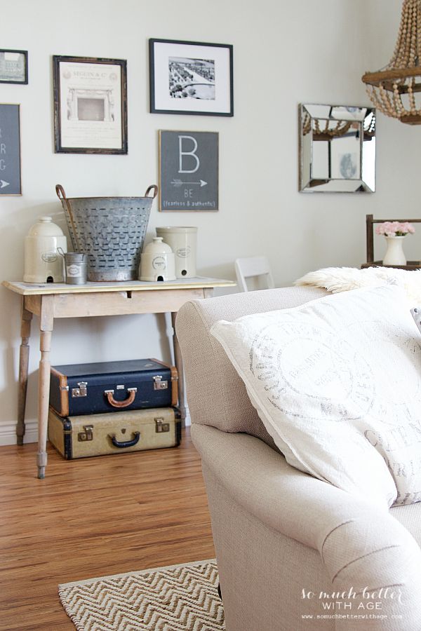 Side table by wall with suitcases underneath it.