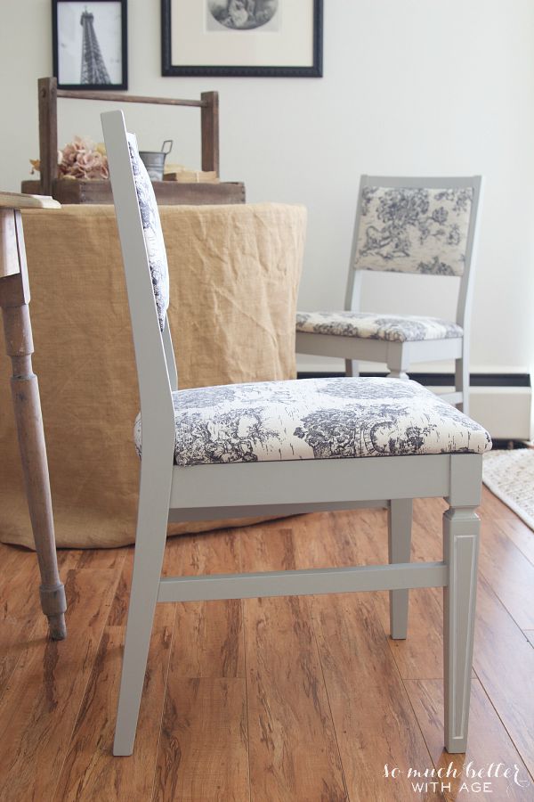 Grey and white toile fabric chair beside a side table.