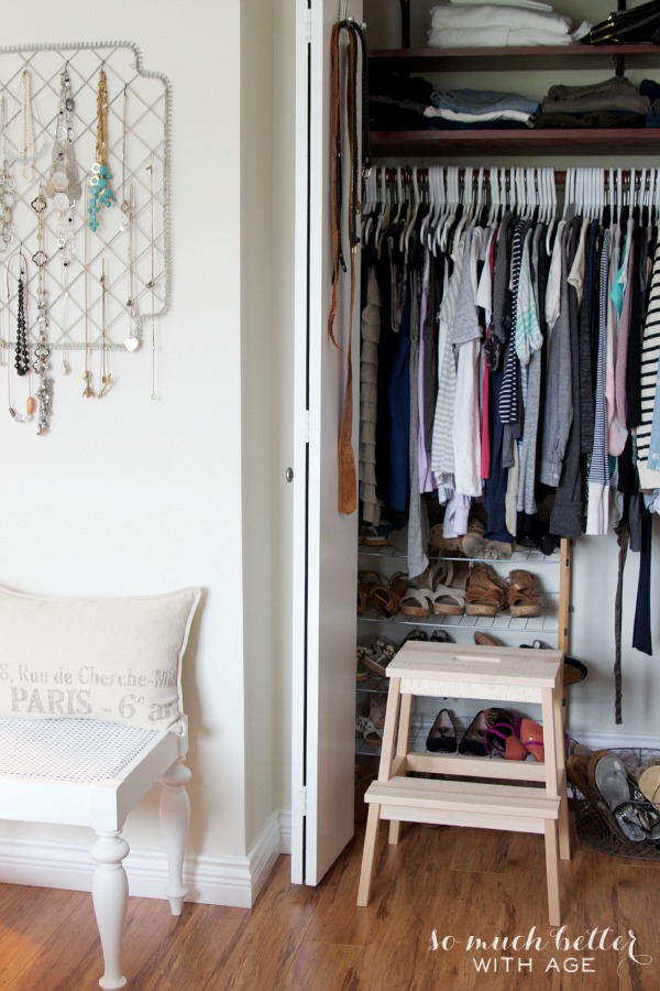 A small closet with a stool in front of it.