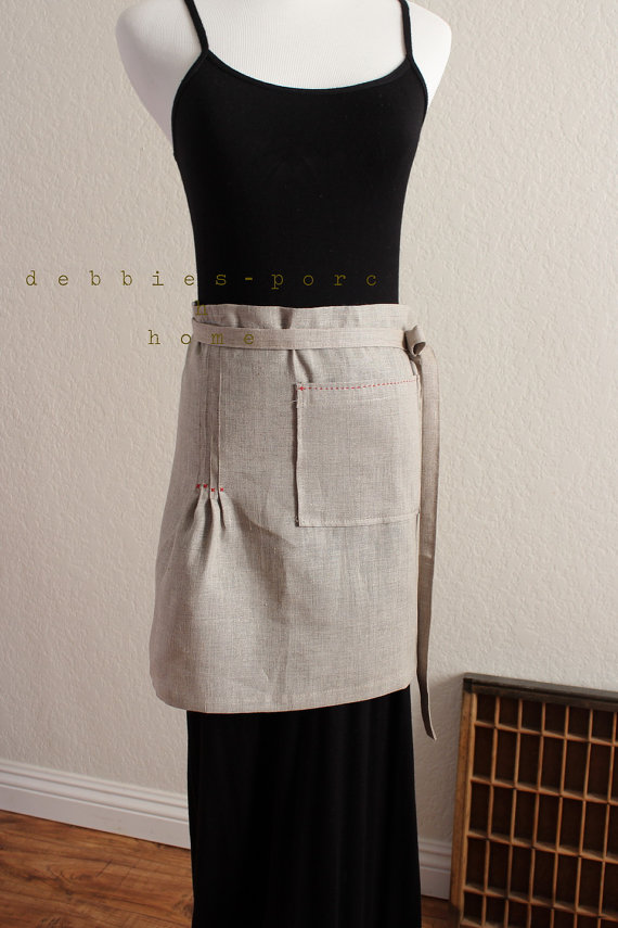 A linen apron with red stitching.