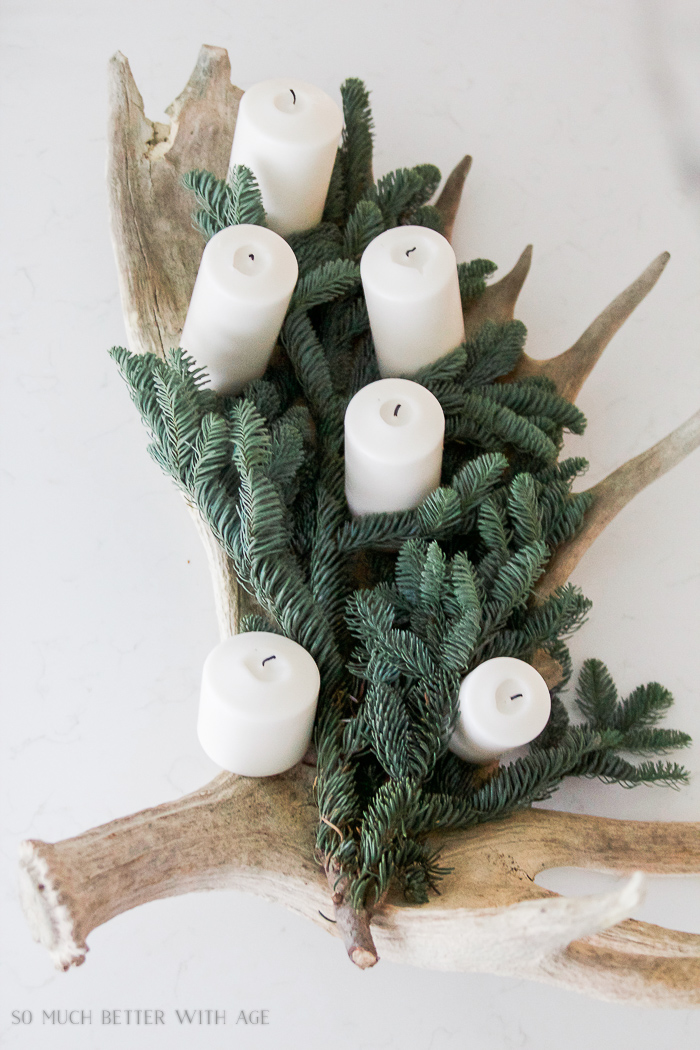Moose antler with greenery and candles in it.