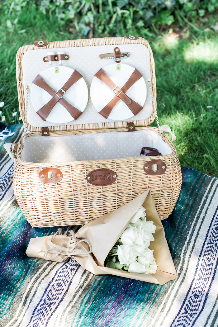 An opened picnic basket with plates and a bottle opener.