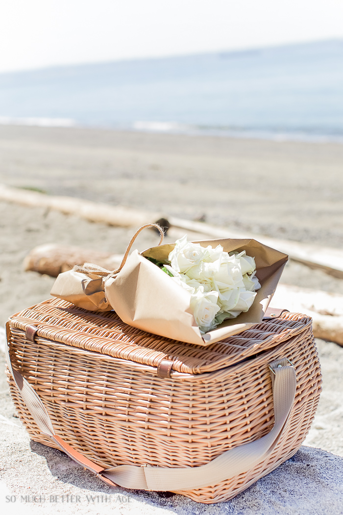 The flowers on top of the picnic basket by the beach.