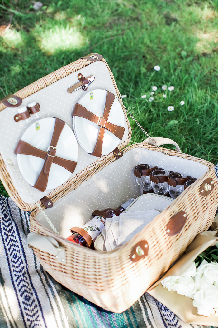 The picnic basket that has wine glasses and a bottle of wine.